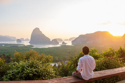 Rear view of man looking at mountains against sky