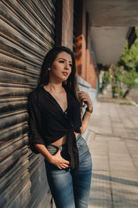Beautiful young woman standing against wall