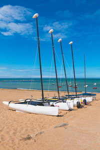Sailboats moored on beach against blue sky