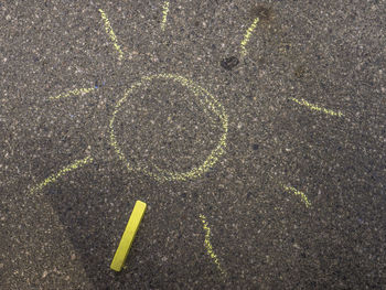 High angle view of sun drawn on road with yellow chalk
