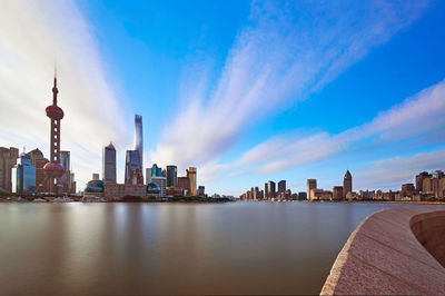 City at waterfront against cloudy sky