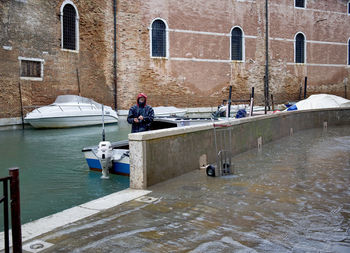 Boats moored in canal against buildings in city during rainy season