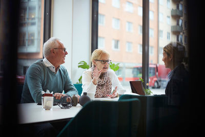 Senior woman with man talking to real estate agent in office