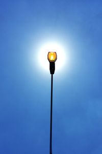 Low angle view of illuminated street light against blue sky