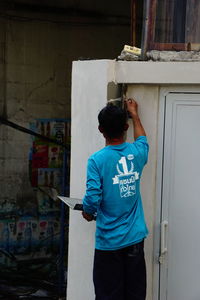 Rear view of man applying cement on wall