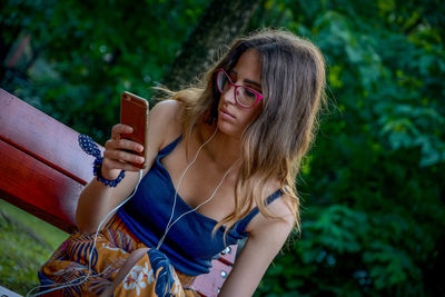 Young woman using mobile phone while sitting in public park