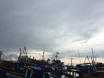 Boats moored at harbor against sky