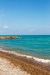 Shore of the beach with stones and jetty in the background. vertical image.