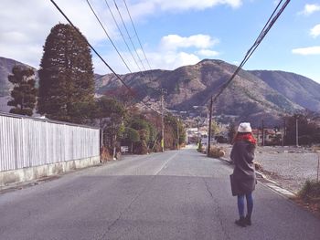 Rear view of woman standing on road against sky