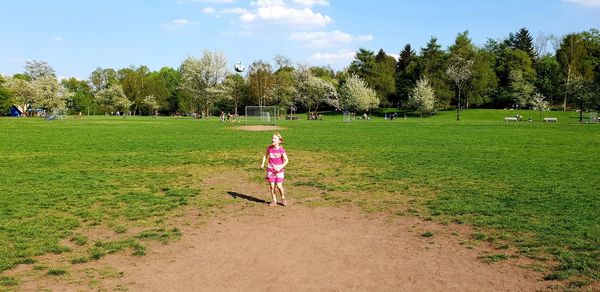 Rear view of girl on field against sky