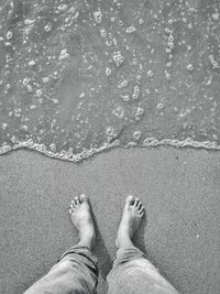 Low section of man standing at beach