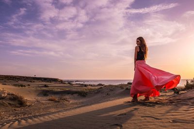 Woman on beach against sky during sunset