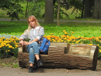 Full length of girl sitting on bench against plants