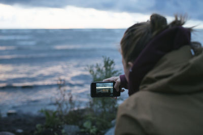 Woman photographing sea using cell phone