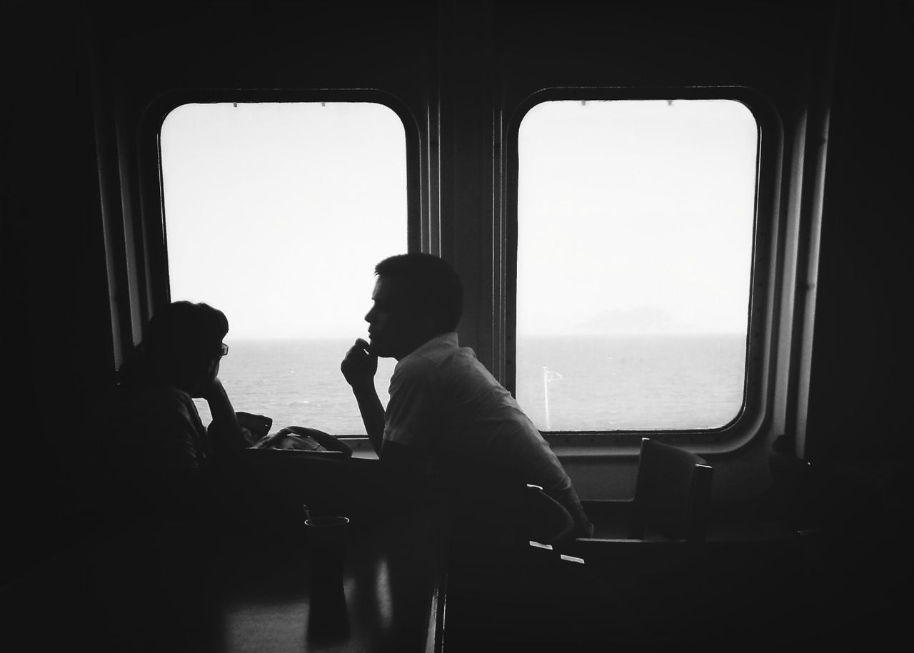 sea, window, lifestyles, indoors, transportation, horizon over water, vehicle interior, leisure activity, rear view, mode of transport, clear sky, travel, water, person, men, sitting, silhouette, looking through window
