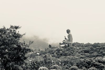 Buddha statue on rock against sky