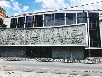 Graffiti on building wall by railroad tracks against sky