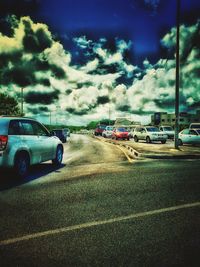 Cars on road against cloudy sky