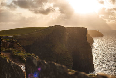 Scenic view of sea by cliff against sky