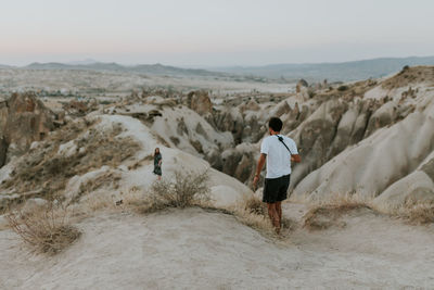 Rear view of man standing on land against sky