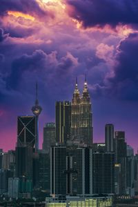 Modern buildings in city against cloudy sky