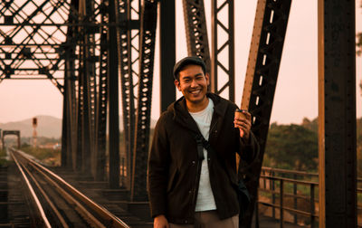 Portrait of smiling man standing on railway bridge