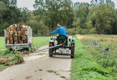 Rear view of farmer driving tractor on field