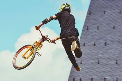 Low angle view of man with bicycle performing a stunt