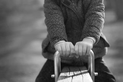 Midsection of kid sitting seesaw