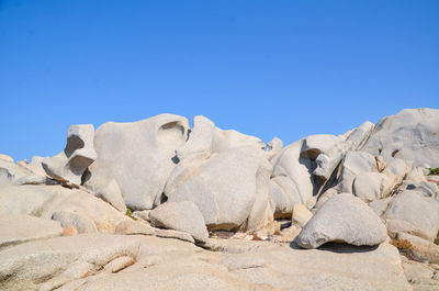 Low angle view of rocks against clear blue sky