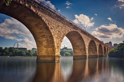 Arch bridge over river against sky