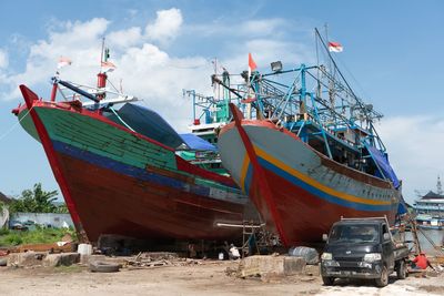 Fishing boats moored on beach against sky