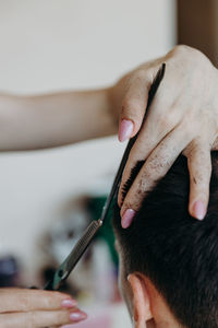 Woman hairdresser cuts hair for male client at home.