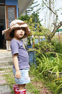 Boy wearing hat standing against plants