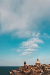 Buildings in city against cloudy sky