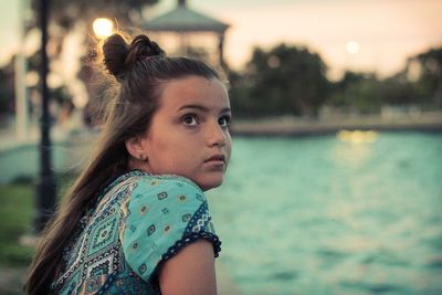 Close-up of thoughtful girl sitting at swimming pool during sunset