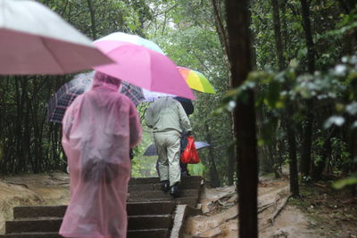 People in raincoat and holding umbrella during rainy day