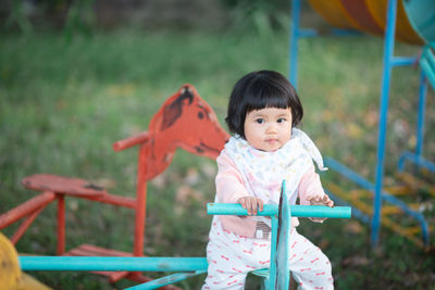 Portrait of cute girl sitting on equipment in playground