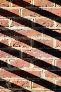 Sunshine casting a shadow pattern on a brick wall