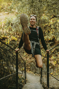 Smiling woman swinging on bridge railing at sierra de hornachuelos, cordoba, spain