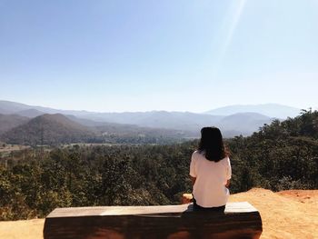 Rear view of woman looking at mountains against sky