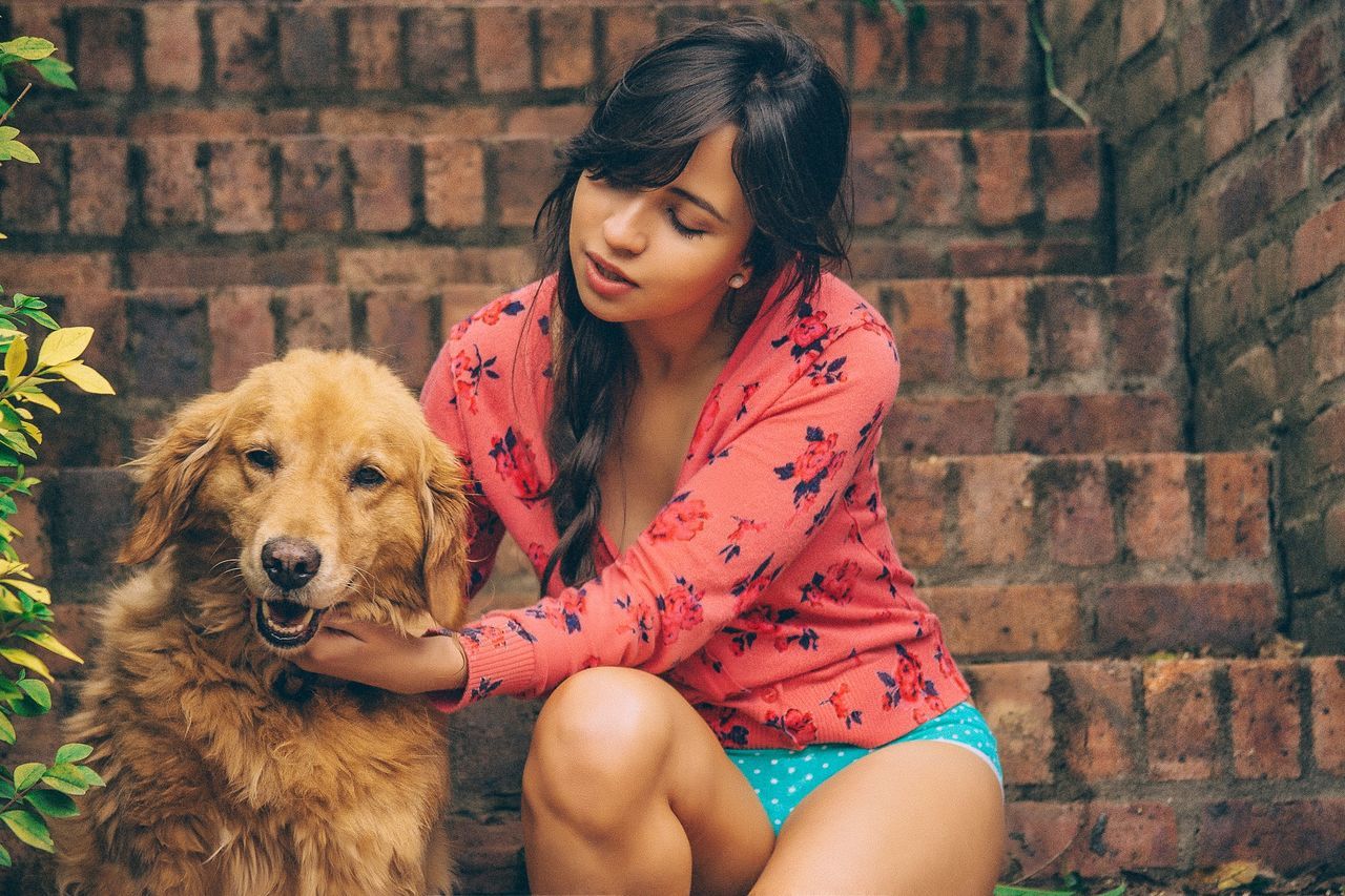 portrait, looking at camera, person, lifestyles, pets, mammal, young adult, domestic animals, animal themes, casual clothing, leisure activity, one animal, dog, three quarter length, front view, smiling, holding, sitting