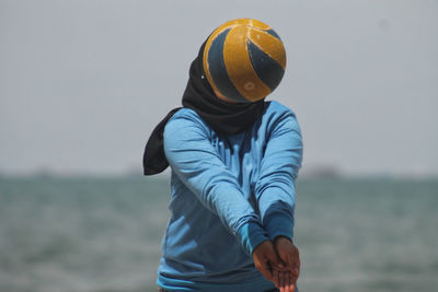 Woman playing volleyball against sky