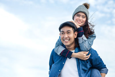 Portrait of smiling young couple against sky