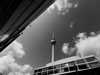 Low angle view of communications tower and building against sky