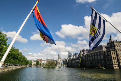 Flags by river against sky