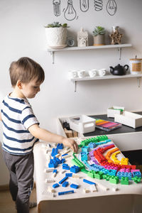 Side view of boy playing with toys at home
