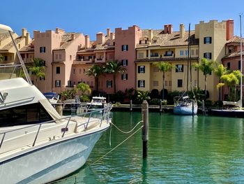 Sailboats moored on canal by buildings in city against sky