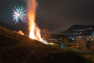 Firework display over mountain at night