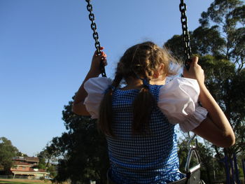 Rear view of girl swinging at park